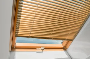 Barna reluxa tetőtéri ablakon, budapesti redőnyszerelés referencia ferde síkú árnyékoláshoz, világos fa kerettel.